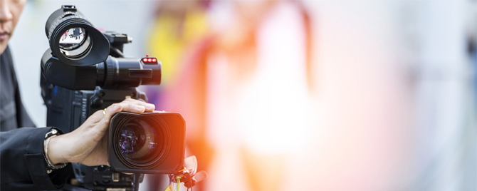 photo - closeup of someone operating a video camera in a brightly lit environment